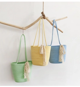 Detail view of woven cotton rope bags in pastel colors with decorative lace ribbons