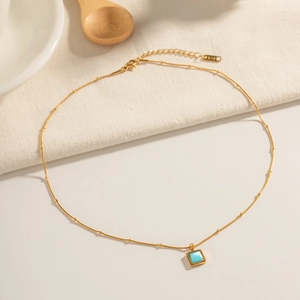 Macro shot of 18K gold chain with turquoise pendant and K18 hallmark on the clasp