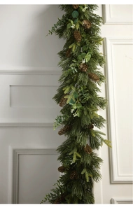 Vertical Christmas garland with pine needles, cones and eucalyptus on white wall