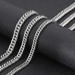 Vue détaillée de colliers en maille gourmette en acier poli sur surface texturée