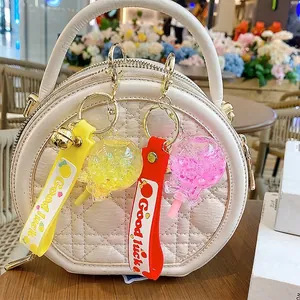 Luminous quicksand lollipop keychain with Good Luck strap on a white quilted handbag