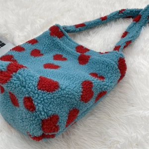 Detail of soft blue faux shearling crossbody bag featuring vibrant red leopard spots