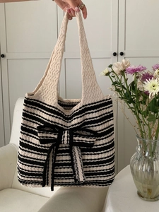 Detail of striped knit tote bag with a large central bow and soft woven texture