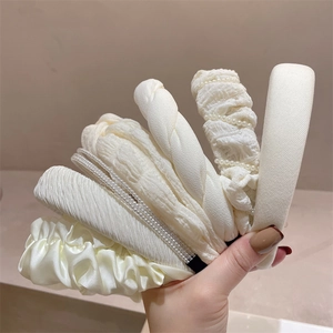 Detailed view of cream fabric headbands featuring elegant pleated textures and pearl accents