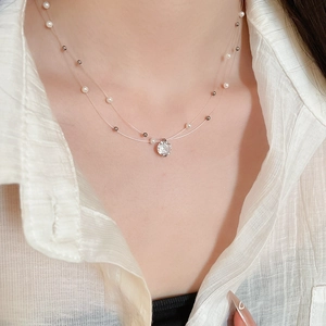 Detail of double-layer necklace featuring white pearls and a bright zircon pendant