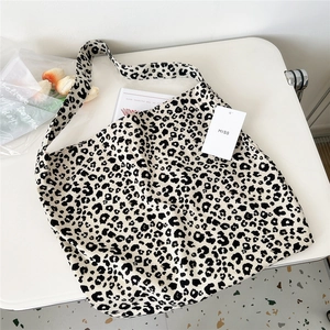Detail shot of leopard print canvas tote bag with wide strap on a white minimal desk