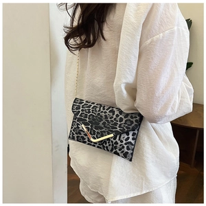 Detail of leopard print envelope clutch with gold V-shaped metal hardware and chain strap