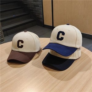 Close-up of three color-block baseball caps with C embroidery on a wooden table