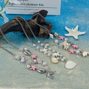 Detail view of colorful shell and starfish necklaces on a sandy beach themed backdrop