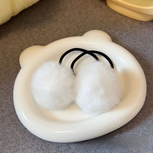 Set of two soft white faux fur pompom hair ties on a cute bear-shaped white plate