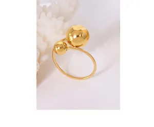 Vue macro d'une bague à billes dorées polies sur un fond de corail blanc décoratif
