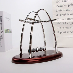 Close-up of five silver Newton's cradle balance balls on a reddish wood base for desk decor