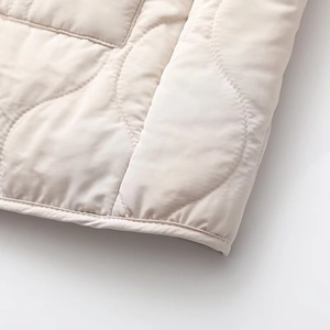Close-up of wave quilted pattern and neat hem detail on a beige padded jacket