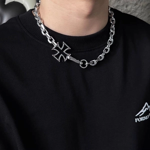 Close-up of a chunky silver cross pendant necklace worn by a model in black hoodie