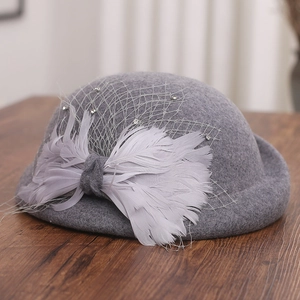 Detail of grey wool fascinator hat featuring delicate mesh veil and feather bow decoration