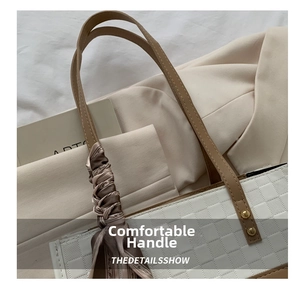 Close-up of white checkered tote bag with brown leather handles and decorative silk scarf