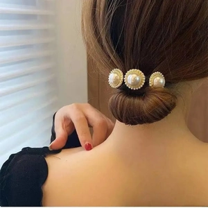Vista de detalle de un pasador dorado con tres perlas grandes en un elegante moño