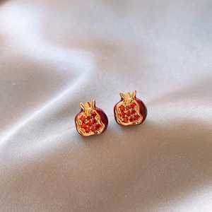 Elegant red pomegranate stud earrings with gold plating and silver pins on grey satin