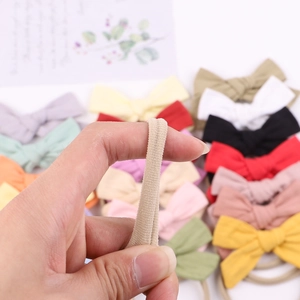 Fascia elastica in cotone beige con fiocco, mostrata tesa per provarne l'elasticità