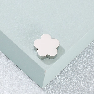 Vue macro d'un pendentif fleur en acier inoxydable argenté sur un support minimaliste
