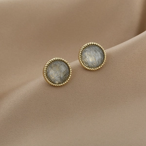 Macro shot of French luxury pearl earrings with gold twisted edge and grey textured center