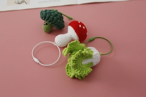 Detailed view of handmade crochet broccoli, mushroom, and lettuce charms with metal rings
