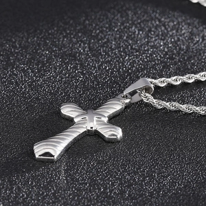 Detailed close-up of a silver textured cross pendant with a twisted rope chain necklace