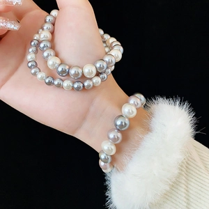 Macro shot of double and single layer pearl bracelets in white and grey on a wrist