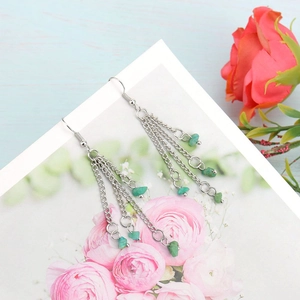 Close-up of bohemian layered silver chain tassel earrings with green natural stone beads