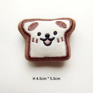 Close-up of a cartoon toast plush brooch with cute dog embroidery measuring 4.5cm by 5.5cm