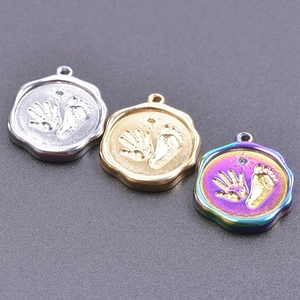 Macro detail of silver, gold, and rainbow stainless steel handprint footprint pendants