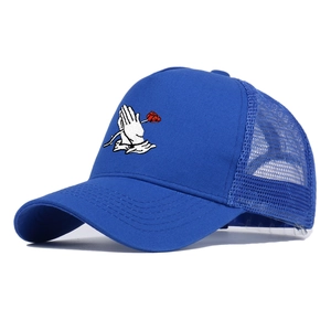 Primer plano detallado de gorra trucker azul con bordado de manos rezando y rosa