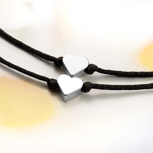 Détail de deux bracelets en corde tressée noire avec breloques en forme de cœur argenté