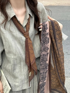 Détail de foulards fins à motifs paisley et dentelle présentés sur le cou et la main
