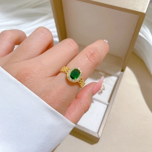 Close-up of gold-plated watchband style ring with oval emerald and zircon pavé