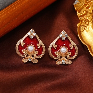 Detail of spade collar pins with red enamel and central pearl inlay on silk background