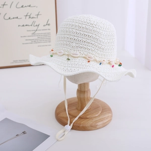 Detailed view of bohemian white crochet straw hat with decorative shells and colorful beads