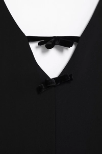 Détail de la robe noire col en V avec deux nœuds décoratifs en velours sur l'encolure