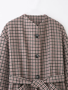 Close-up of purple plaid coat featuring black buttons and a matching waist belt detail