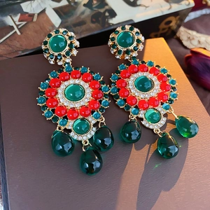 Detailed close-up of vintage gold earrings with green and red gems on a jewelry box