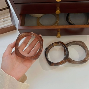 Detailed view of amber and marble resin bangle with irregular geometric design on wrist