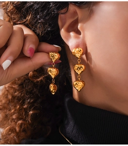 Détail de boucles d'oreilles cœur dorées texturées portées par un mannequin féminin