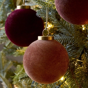 Velvet 8cm Christmas ball ornaments in deep red and pink hanging on a lush green tree
