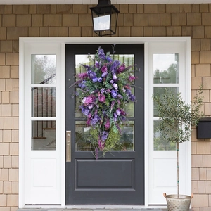 Close-up of artificial purple tulip and lavender wreath hanging on a black wooden door
