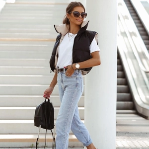 Outdoor street style view of a black padded puffer vest with stand-up collar and zipper
