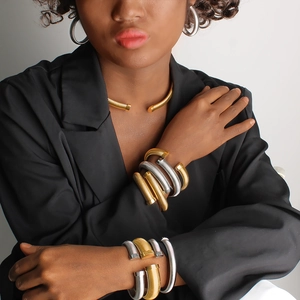Close-up of a model wearing tiered gold and silver metallic coil chokers and bracelets