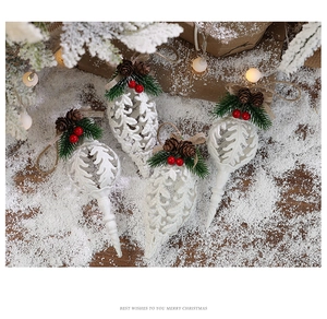 Detail of white festive pendants with pine cones and berries on a snowy wood surface