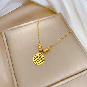 Macro shot of gold titanium steel necklace featuring a hollow Double Happiness pendant