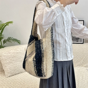 Detail of plush fleece shoulder bag with blue stripes shown on a model's arm