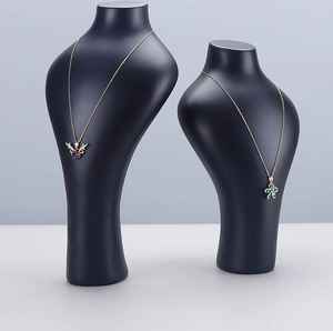 Macro detail of black matte necklace busts showing gold pendants with crystal inlays